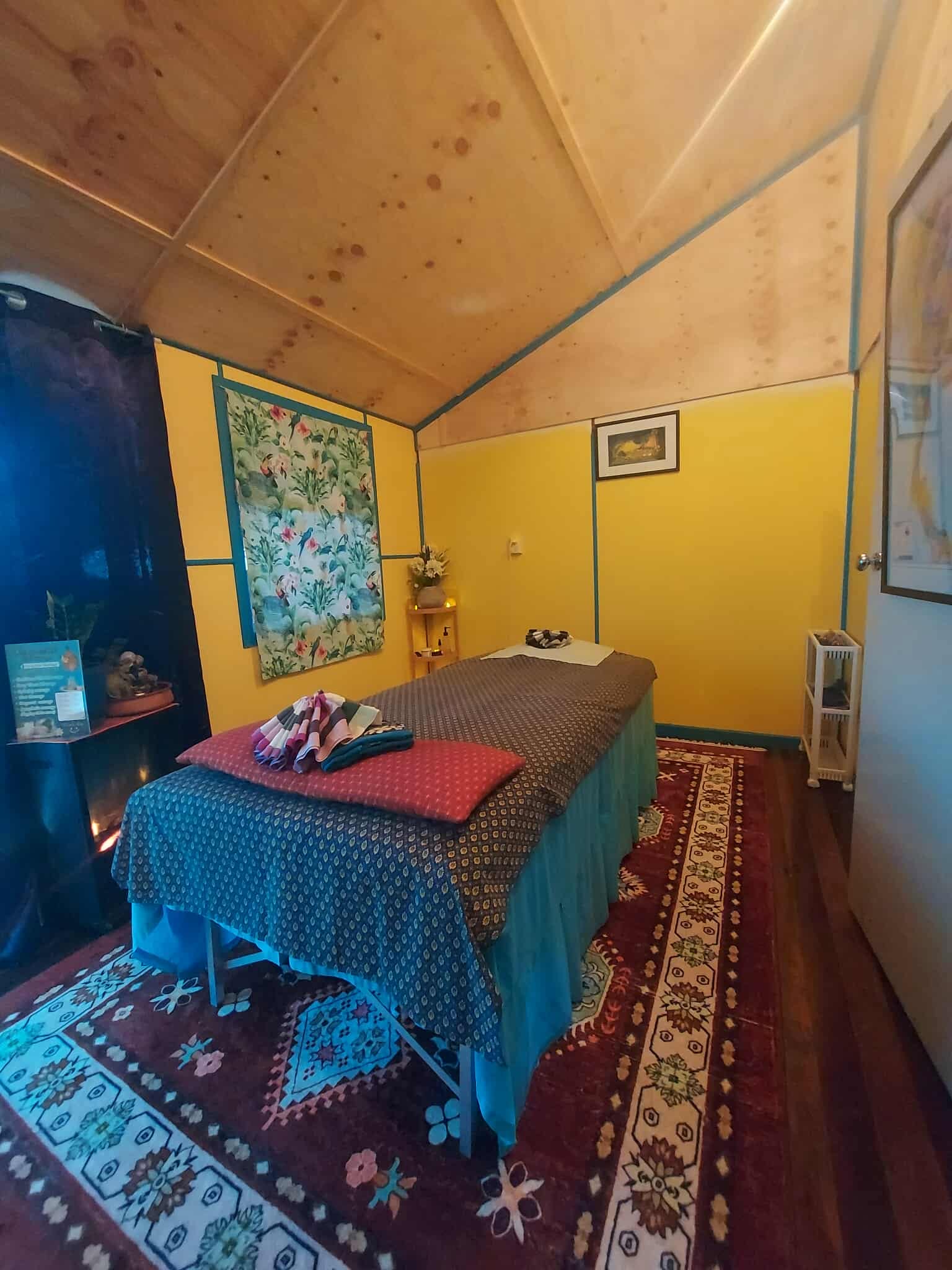 Treatment room with yellow walls, teal trim and a draped massage table