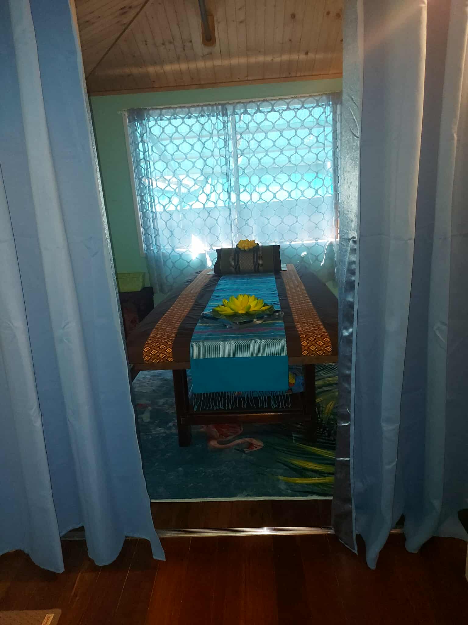 View through a curtained doorway to a second massage table